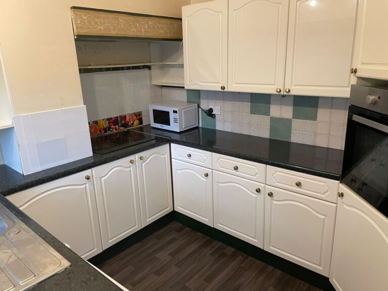 Shared HMO kitchen after clean — U-shaped layout, worktops and splashback polished.