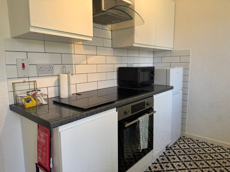 Serviced apartment kitchenette after clean — hob, splashback and surfaces sanitised.