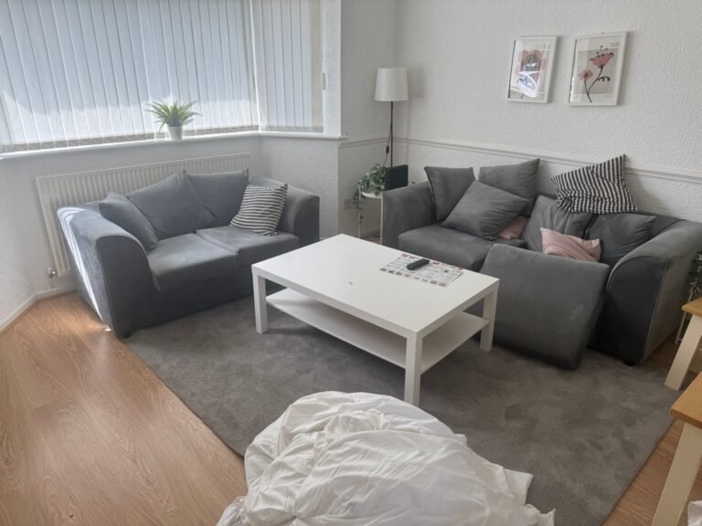 Airbnb lounge before turnaround — sofa cushions removed, clutter on floor.